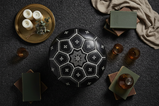 Moroccan artisan hand-stamping intricate geometric patterns onto a genuine leather pouf in a traditional Marrakech workshop
