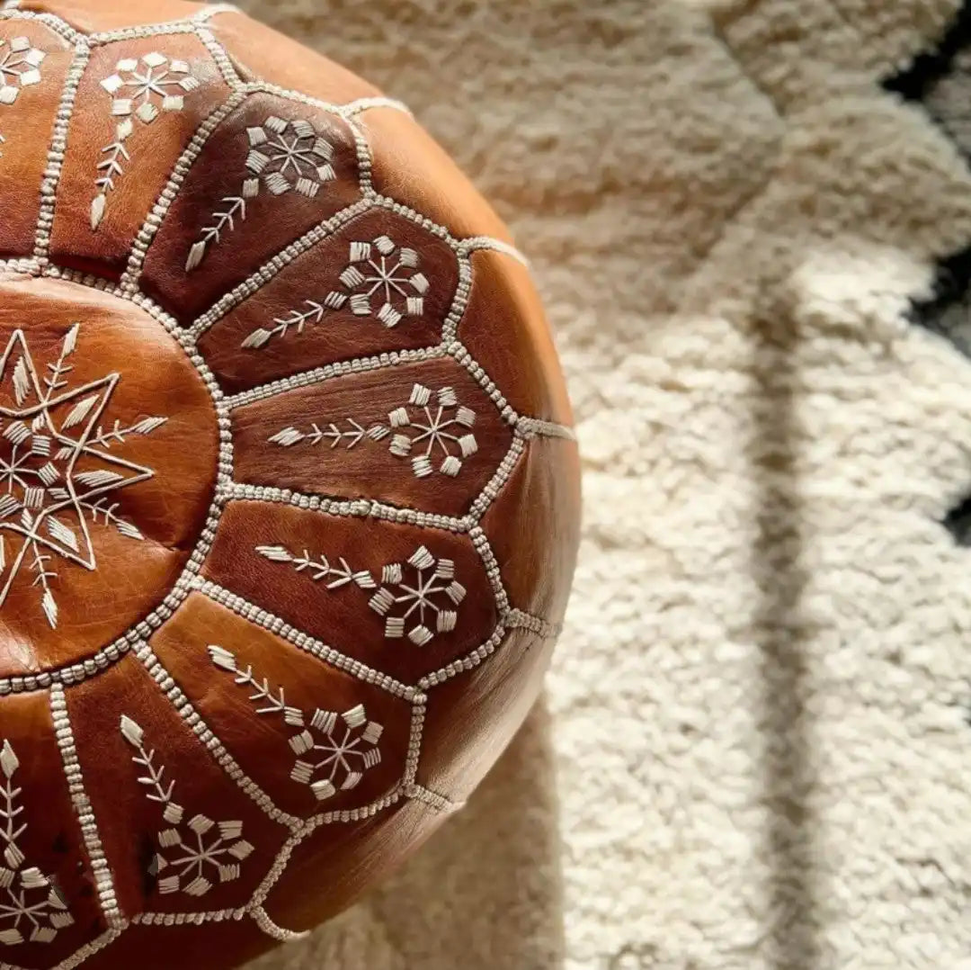 Brown leather Moroccan pouf with intricate white embroidery