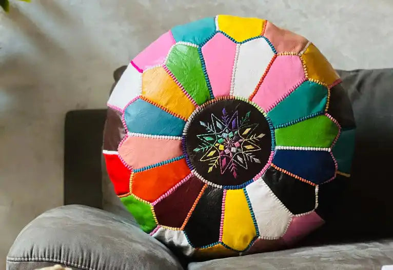 A colorful patchwork leather pouf with intricate embroidered designs.